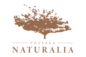 Logotipo da pousada Naturalia contendo a imagem de uma árvore com folhas se soltando ao vendo.